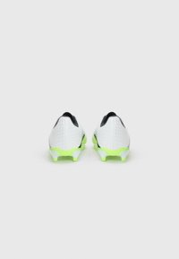 White soccer cleats with textured synthetic upper, neon green accents on sole, black detailing, and a sleek design for enhanced performance.