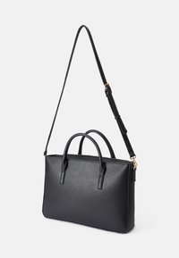 Black vegan leather handbag with dual top handles, adjustable shoulder strap, and a zip closure. Smooth texture; minimalist design.