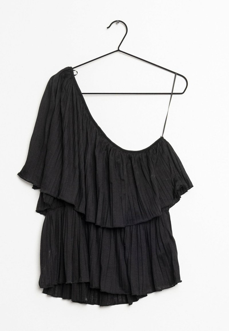 Blouse noire à épaules dénudées avec des couches froncées, bénéficiant d'une texture légère et d'une seule bretelle réglable, accrochée à un cintre en métal noir.