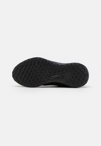 SchwarzeSport-Schuhsohle mit einem strukturierten Muster für Grip, versehen mit ovalen und runden Vertiefungen. Nike-Logo im Zentrum sichtbar.