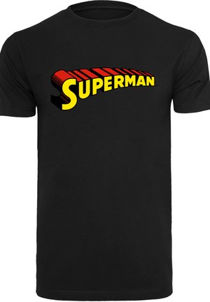 Čern�é bavlněné tričko s velkým, vícebarevným logem "Superman" v žluté barvě s červenými akcenty a stínovaným písmem přes hruď.