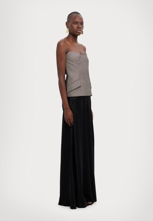 Grijs en wit gestreepte strapless top, gelaagd ontwerp, gecombineerd met een lange zwarte, vloeiende rok. Gouden oorringen voegen een decoratieve accenten toe.