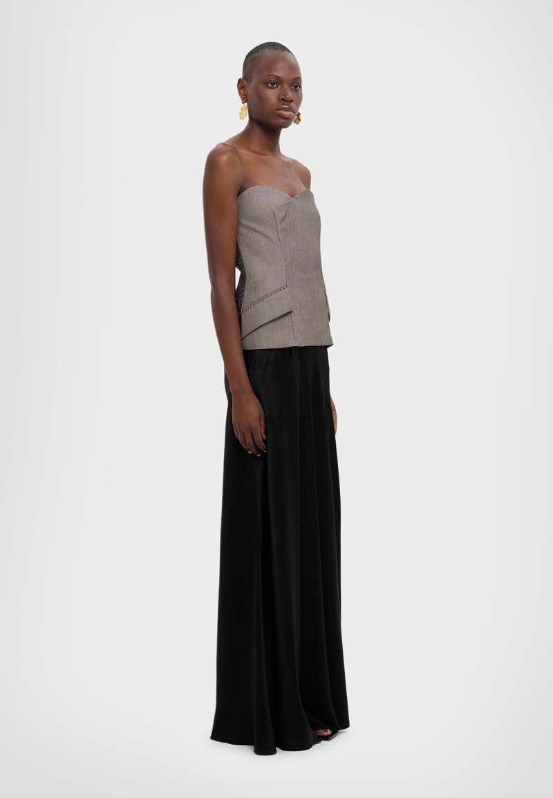 Grijs en wit gestreepte strapless top, gelaagd ontwerp, gecombineerd met een lange zwarte, vloeiende rok. Gouden oorringen voegen een decoratieve accenten toe.