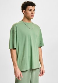 Oversized T-shirt met korte mouwen in lichtgroene katoen, met een ronde halslijn en een subtiele logo-accent nabij de zoom. Gecombineerd met bijpassende broek.