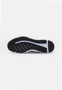 Suola di scarpa da ginnastica nera con superficie in gomma texturizzata, caratterizzata da una linea bianca ondulata e fori di ventilazione per aderenza e traspirabilità.