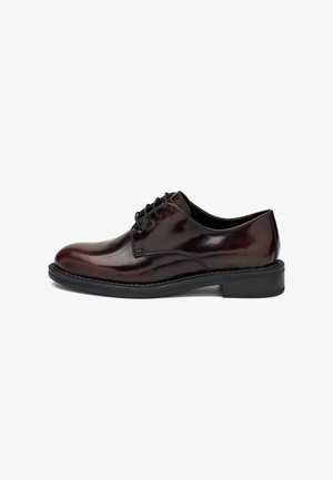 Zapato Oxford de piel pulida en marrón oscuro para hombre, con cordones y suela negra, mostrado en perfil lateral sobre un fondo blanco.