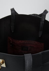 Czarna skórzana torba torebka o teksturowanym wykończeniu, wewnętrznie podszewkowana ciemnym materiałem, z zamykaną na zamek kieszenią i logo Furla.