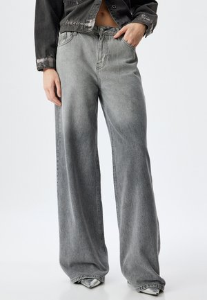 Jeans de mezclilla gris de pierna ancha con un acabado desgastado, que presentan un diseño de cinco bolsillos y pasadores para cinturón. La tela tiene un aspecto texturizado.