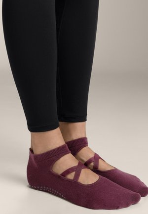 Burgundske pletene baletne nogavice s križnimi trakovi, ki imajo teksturiran podplat z delno gripom. Nosi se z črnimi leggins.