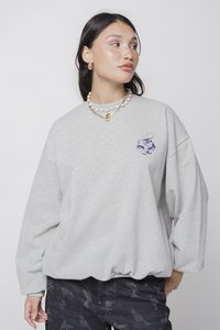 Sudadera de color gris claro con un corte holgado, dobladillo acanalado y diseño bordado que presenta una ilustración colorida en el lado izquierdo del pecho.