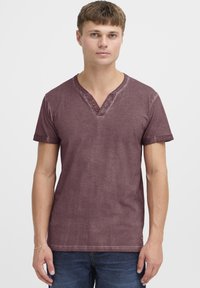 Maron V-hals t-skjorte laget av myk bomull. Korte ermer, tre-knappers pløse, og en lett slitt tekstur. Tettsittende design.