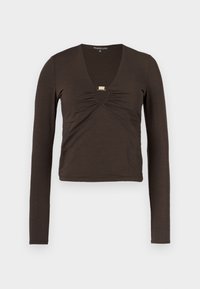 Haut marron à manches longues avec un décolleté en V profond, tissu froncé au niveau de la poitrine, et un détail argenté sous l'encolure.