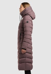 Garšs, pūkains mēteli maiga purpura krāsā ar augstu apkakli un regulējamu kapuci, ar melnām akcentēm un sānu rāvējslēdzēja kabatām.