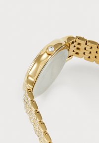 Gold-tone watch with a round case, textured finish, and a crystal-embellished crown. Features a linked metal bracelet with clear accents.