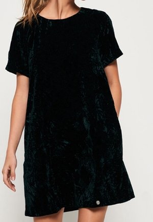 Dunkelgrünes Samtkleid mit lockerem Schnitt, kurzen Ärmeln und rundem Ausschnitt; verfügt über eine dezente Vordertasche und einen dekorativen Knopf.