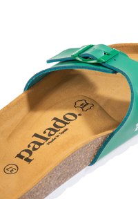 Sandalo in pelle verde con cinturino regolabile e fibbia in metallo, dotato di una soletta in sughero marrone e suola in gomma bianca. Logo "palado" stampato all'interno.