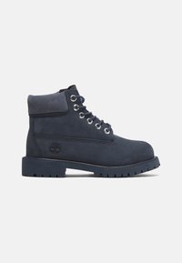 Botas de tobillo de ante azul marino con cordones en la parte delantera, puntera redonda, cuello acolchado y suela de goma resistente con surcos de tracción.