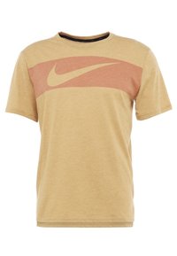 Camiseta de manga corta color beige con cuello redondo y una franja roja horizontal en el pecho que presenta un gran logo de Nike.