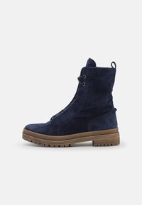 Bottines en suède bleu marine avec une finition texturée, fermeture à lacets et semelle en caoutchouc avec un motif strié.