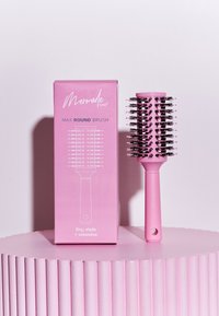 Cepillo de pelo redondo con un mango de plástico rosa y cabeza cilíndrica, que presenta cerdas negras escalonadas. Acompañado de un embalaje rosa a juego.