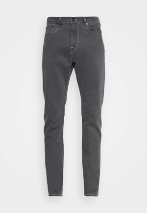 Tummanharmaat slim fit -farkut, joissa on etutaskut, vyölenkit ja nappikiinnitys, valkoista taustaa vasten esitettynä.