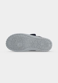 Semelle de chaussure grise avec un motif en zigzag, indication de taille "25,", étiquette non-marking et nom de la marque "Superfit" visibles au-dessous.