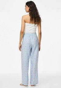 Pantalons bleu clair, coupe décontractée avec un motif rayé, taille élastique et petite broderie florale rouge sur l'ensemble. Design casual.