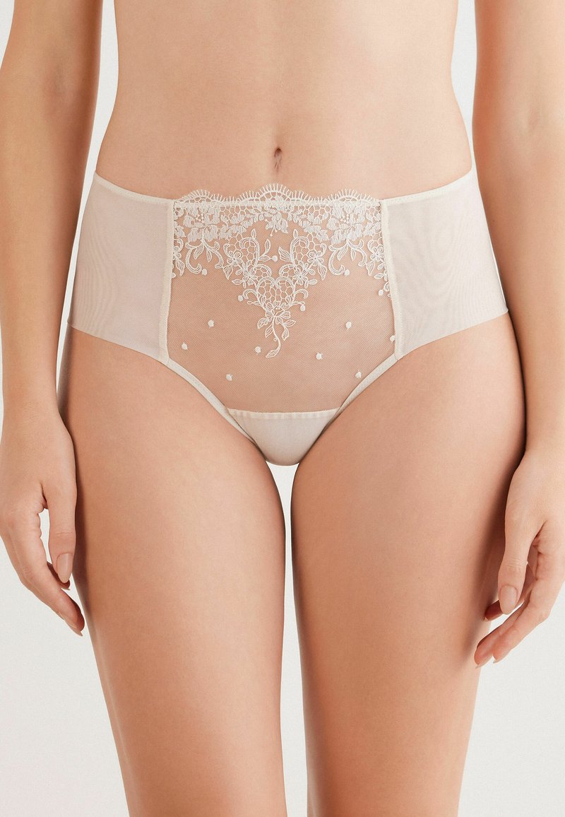 Mutandine beige a vita alta realizzate in rete trasparente con ricami floreali e piccoli dettagli. Presentano un bordo in pizzo lungo la vita e bordi lisci.