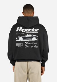 Black hooded sweatshirt with large white text "Pegador" and graphic of a car on the back. Features ribbed cuffs and hem, casual fit.