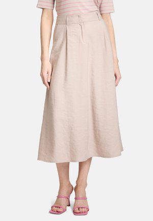 Jupe midi en lin beige clair avec des plis et une taille haute. Portée avec des talons roses à lanières, soulignant un design épuré et minimal.