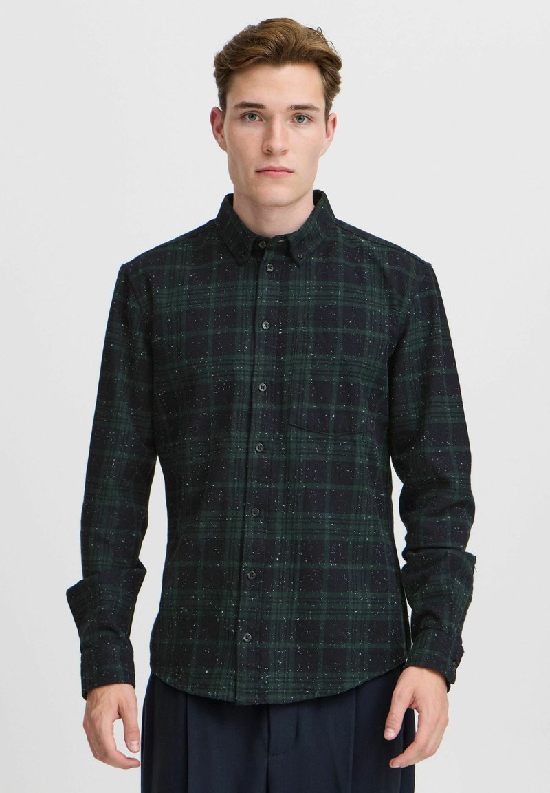 Cămașă cu carouri verzi și negre, cu butoni, un buzunar pe piept, mâneci lungi și textură presărată. Material din bumbac, design casual.