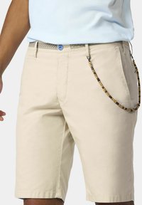 Beige katoenen shorts met een rechte snit, voorzien van een blauwe knoop en een decoratieve ketting van bruine en gele kralen aan de rechterkant.