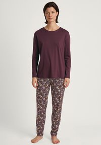 Langsleeve paars top gecombineerd met gestreepte, aansluitende pyjamabroek met bloem- en abstracte ontwerpen in diepe kleuren. Zacht, lichtgewicht stof.
