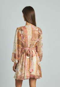 Sukienka we florystyczny wzór z miękkiej, przezroczystej tkaniny. Posiada falbaniaste rękawy, ściągniętą talię z wiązaniem oraz rozszerzany dół w odcieniach różu i złota.