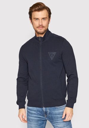 Giacca zip-up blu navy in cotone con colletto alto e logo tono su tono sul petto; presenta maniche lunghe e polsini aderenti.