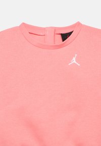 Ροζ φούτερ με στρογγυλή λαιμόκοψη, διακοσμημένο με μικρό λευκό λογότυπο Jordan στο στήθος και λεπτομέρεια ανοίγματος στην πλάτη. Απαλή υφή υφάσματος.