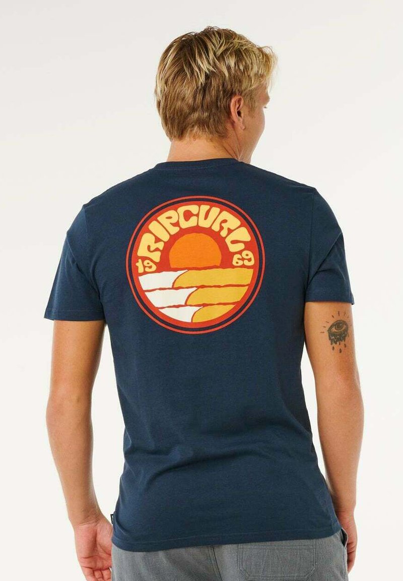 T-shirt en coton bleu marine avec un graphisme rétro circulaire représentant un coucher de soleil et des vagues en orange et jaune au dos, col rond.