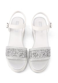 Sandali bianchi con una fascia argentata glitterata, supporto per le dita e il tallone, fibbia regolabile alla caviglia e soletta imbottita per il comfort.