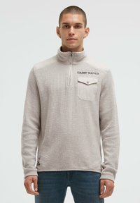 Hellbeige Pullover mit Viertelreißverschluss aus strukturiertem Stoff. Verfügt über eine Tasche mit Knopf, "CAMP DAVID" Stickerei und einen lockeren Schnitt.