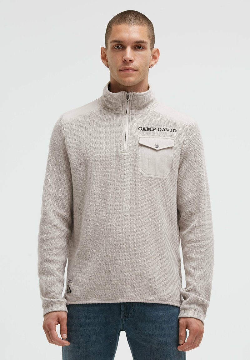 Hellbeige Pullover mit Viertelreißverschluss aus strukturiertem Stoff. Verfügt über eine Tasche mit Knopf, "CAMP DAVID" Stickerei und einen lockeren Schnitt.