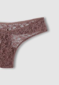Tanga in pizzo color malva con motivo floreale, caratterizzato da bordi delicati e una cintura elastica per il massimo comfort. Il materiale semitrasparente aggiunge texture.