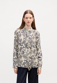Long-sleeve blouse featuring a paisley pattern in blue and beige on a cream background, with button-up front and ruffled detailing.