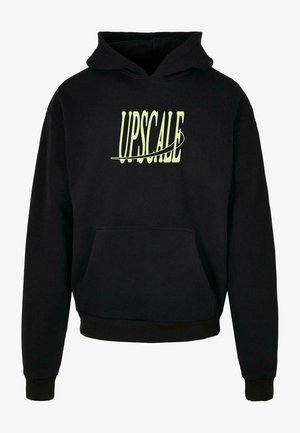 Sudadera negra de material suave con bolsillo tipo canguro y capucha con cordón. La palabra "UPGRADE" en letras grandes de color verde claro en la parte frontal.