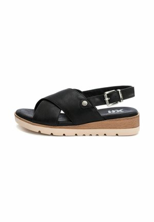 Sandalia de cuero negro con un diseño de correas cruzadas, correa ajustable y una suela ligera y contorneada con un acento similar a la madera.