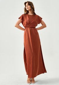 Rjavkastna maksi obleka iz gladkega satena, ki ima kratke, ohlapne rokave, ovit zgornji del in stranski razporek za dodaten poudarek.