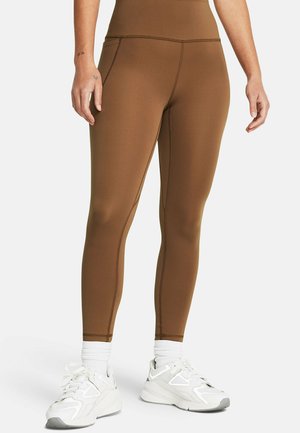 Brown leggings made from stretchy material with a high waistband, featuring flat seams and a fitted design, paired with white sneakers.