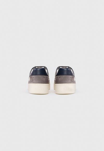 Tenisi din suede bleumarin și gri cu o talpă din cauciuc crem. Caracteristicile includ modele perforate și branduirea pe toc. Design simplu cu șireturi.