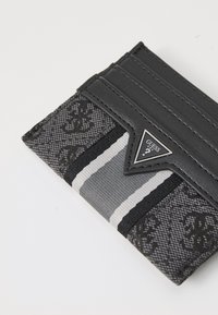 Portefeuille noir en cuir et tissu avec un design à motifs, plusieurs emplacements pour cartes et un accent logo en forme de triangle. Bandes argentées incluses.
