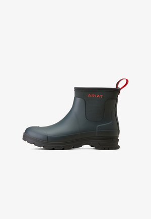 Black rubber ankle boot with a textured surface, red accents, and a pull tab. Features a flexible design and rugged sole for traction.