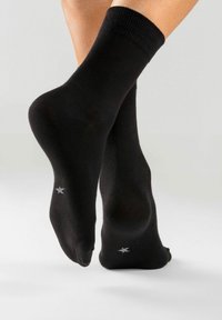 Schwarze Baumwollcrew-Socken mit gerippten Bündchen, glatter Textur und einem kleinen silbernen Sternmuster an den Seiten.